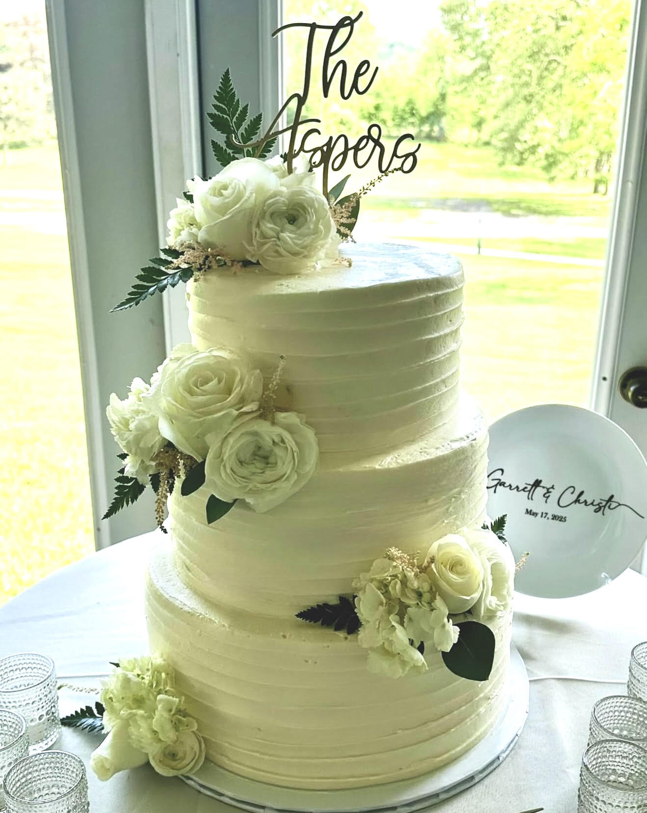 A white tiered wedding cake trimmed with fresh greenery